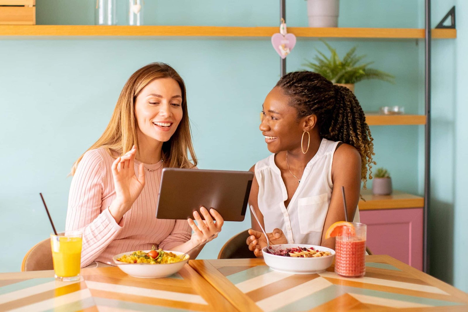 Young black and caucasian woman having good time, drinking fresh